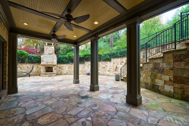 view of terrace with ceiling fan and an outdoor stone fireplace