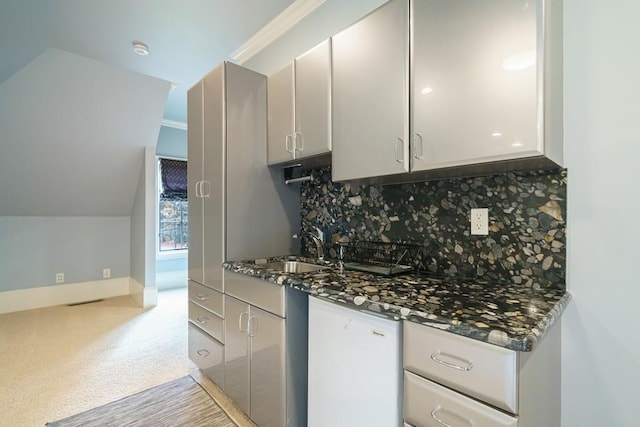 kitchen with lofted ceiling, light colored carpet, tasteful backsplash, and dark stone countertops