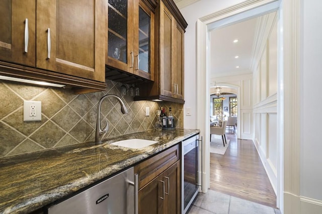 kitchen featuring light hardwood / wood-style floors, beverage cooler, crown molding, dark stone countertops, and sink