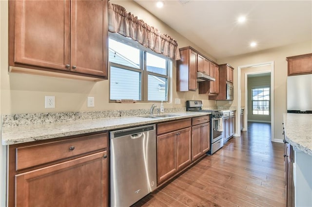 kitchen with light stone counters, sink, hardwood / wood-style floors, and appliances with stainless steel finishes