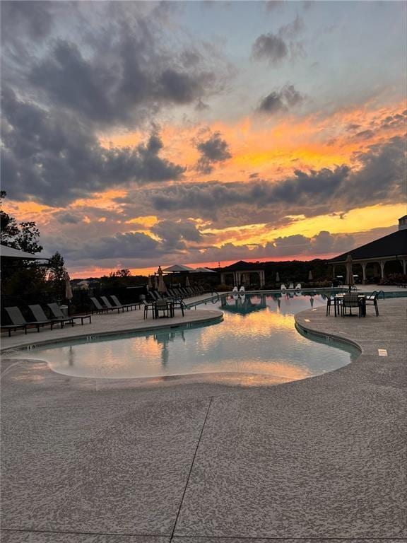 pool at dusk featuring a patio