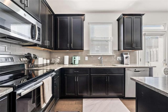kitchen featuring backsplash, a sink, a wealth of natural light, and stainless steel appliances