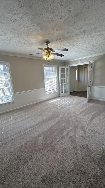 unfurnished living room with carpet floors, a ceiling fan, and a textured ceiling