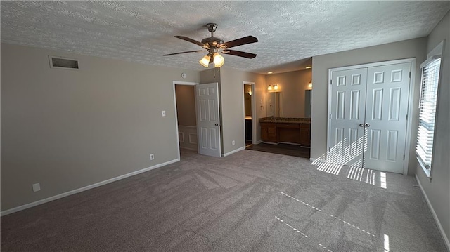 unfurnished bedroom with a textured ceiling, carpet, visible vents, and baseboards