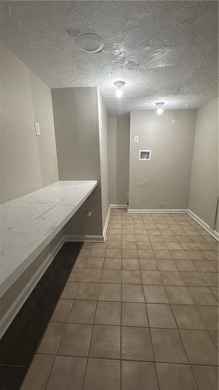 interior space with tile patterned flooring, baseboards, and a textured ceiling