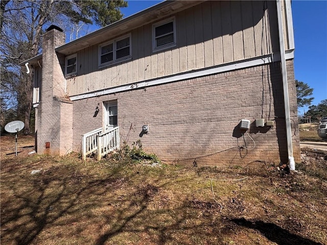 view of side of property with a chimney and brick siding