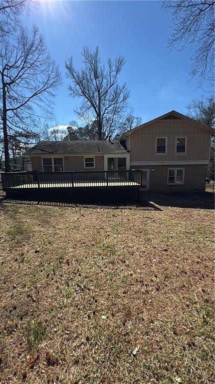 back of house featuring a lawn and a wooden deck