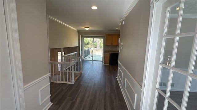 hallway with visible vents, dark wood finished floors, crown molding, and an upstairs landing