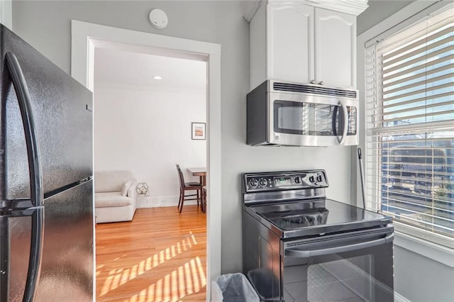 690 Piedmont Ave NE Unit 17, Atlanta, GA 30308 - kitchen with black appliances, white cabinetry, baseboards, and light wood-style flooring
