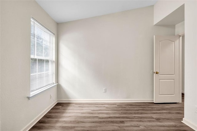 spare room with wood-type flooring and vaulted ceiling