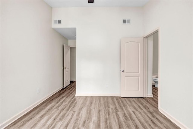 empty room with light hardwood / wood-style floors and a towering ceiling