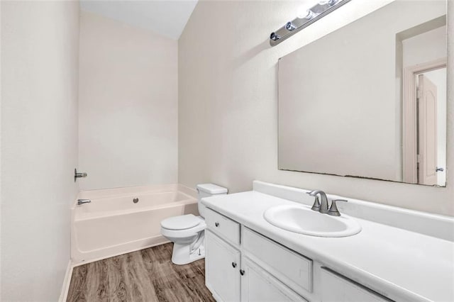 bathroom featuring a washtub, vanity, hardwood / wood-style flooring, and toilet