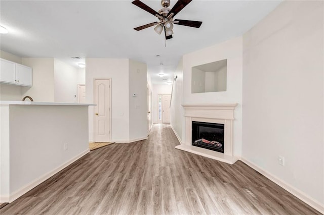 unfurnished living room with ceiling fan and wood-type flooring