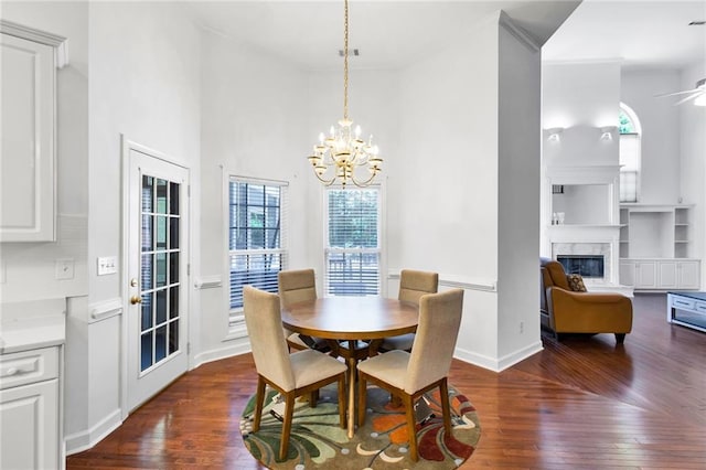 385 Windermere Cir, Newnan, GA 30265 - dining area featuring dark wood-style floors, a chandelier, a fireplace, a towering ceiling, and baseboards