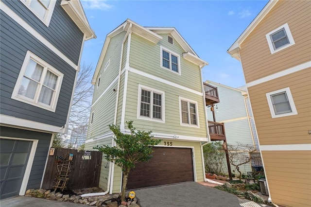 view of front facade with aphalt driveway, a balcony, fence, and a garage