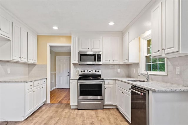 kitchen featuring white cabinets, decorative backsplash, appliances with stainless steel finishes, and a sink