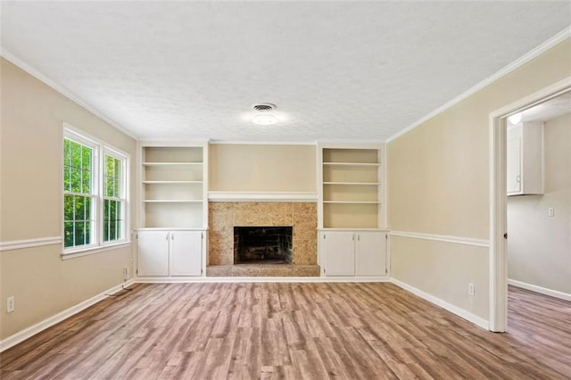 unfurnished living room with visible vents, baseboards, wood finished floors, and built in shelves