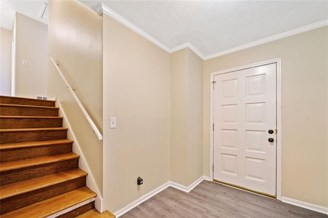 entrance foyer with baseboards, ornamental molding, wood finished floors, and a textured ceiling