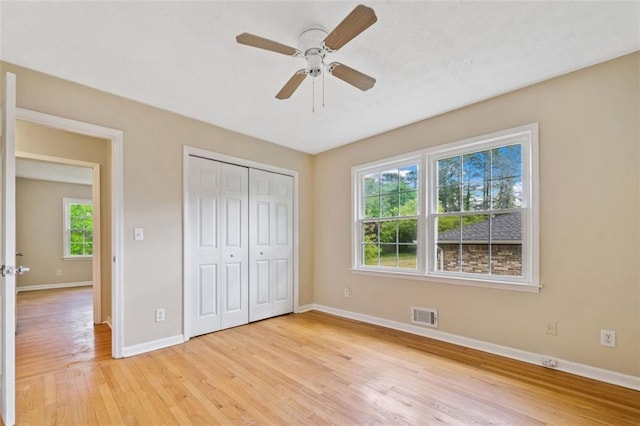 unfurnished bedroom featuring light wood finished floors, baseboards, visible vents, and multiple windows