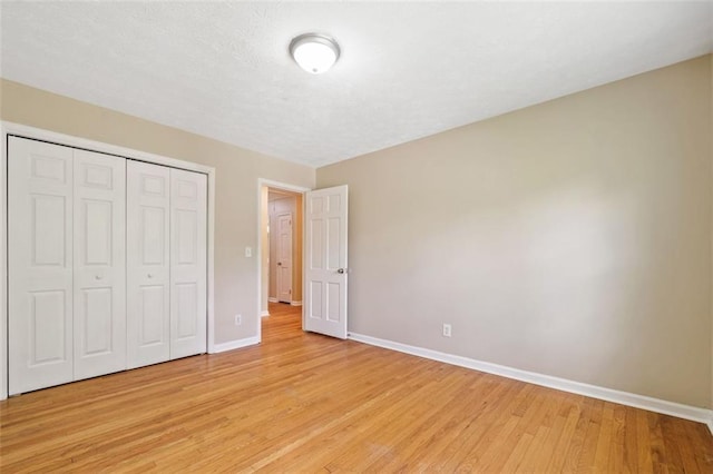 unfurnished bedroom with light wood-style floors, a closet, and baseboards