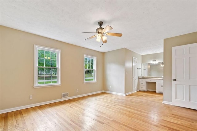 interior space featuring built in desk, visible vents, light wood-style floors, baseboards, and ceiling fan
