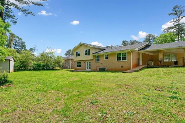 rear view of property featuring a lawn, an outdoor structure, brick siding, and central AC