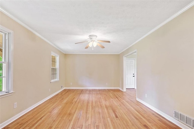 empty room featuring visible vents, light wood-type flooring, crown molding, baseboards, and ceiling fan
