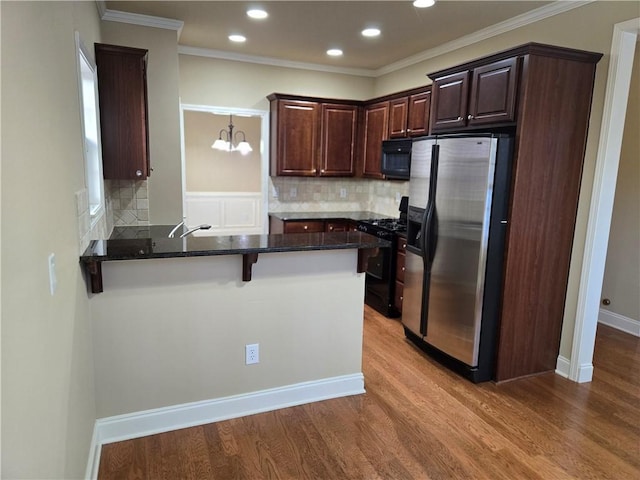 2110 Retreat Haven Ln, Dacula, GA 30019 - kitchen featuring black appliances, a peninsula, wood finished floors, tasteful backsplash, and recessed lighting