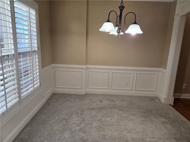 2110 Retreat Haven Ln, Dacula, GA 30019 - unfurnished dining area with healthy amount of natural light, a chandelier, a decorative wall, wainscoting, and carpet