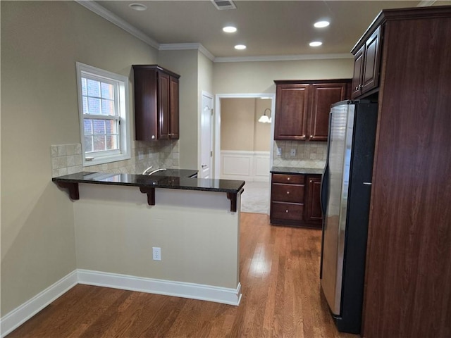 2110 Retreat Haven Ln, Dacula, GA 30019 - kitchen with freestanding refrigerator, a peninsula, crown molding, dark wood finished floors, and a breakfast bar area