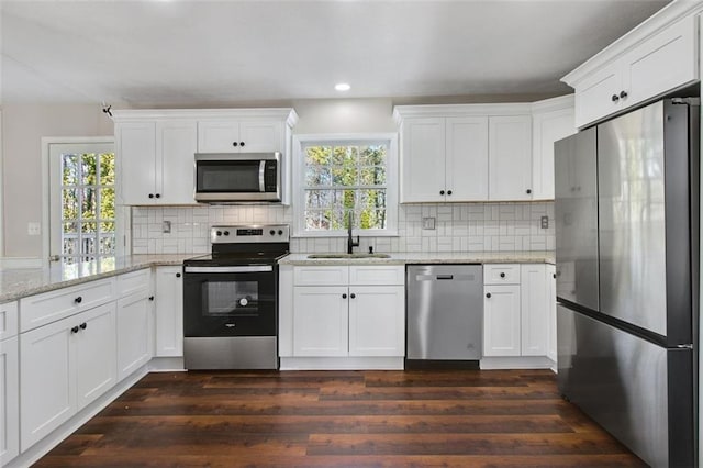 kitchen with white cabinetry, sink, light stone countertops, stainless steel appliances, and tasteful backsplash