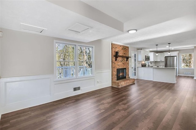 unfurnished living room featuring dark hardwood / wood-style floors, sink, and a fireplace