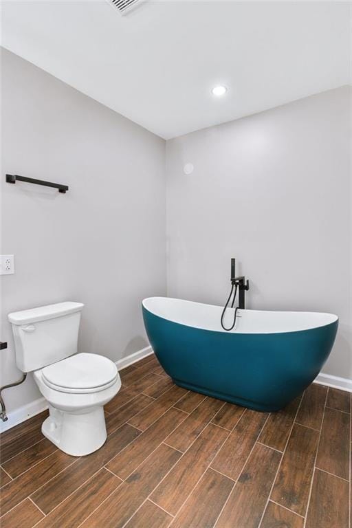 bathroom with a tub to relax in and toilet