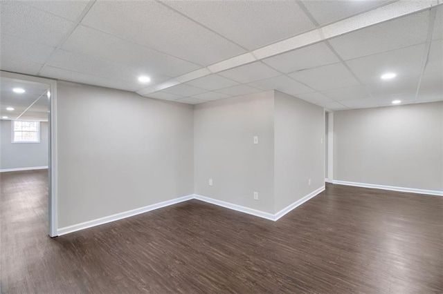 basement with a paneled ceiling and dark hardwood / wood-style floors