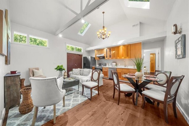 interior space featuring high vaulted ceiling, a skylight, light hardwood / wood-style floors, sink, and a notable chandelier