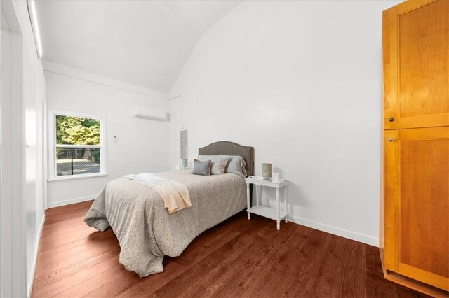 bedroom featuring lofted ceiling, dark hardwood / wood-style flooring, and a wall mounted air conditioner