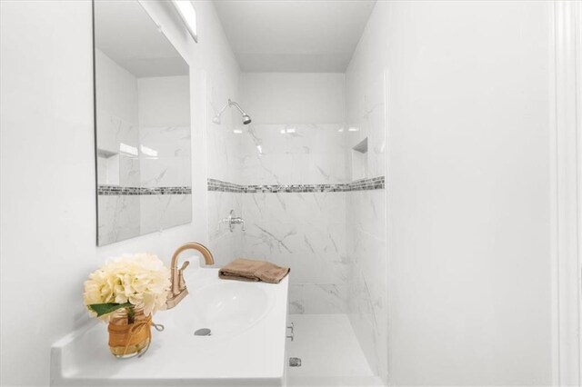 bathroom featuring tiled shower and vanity