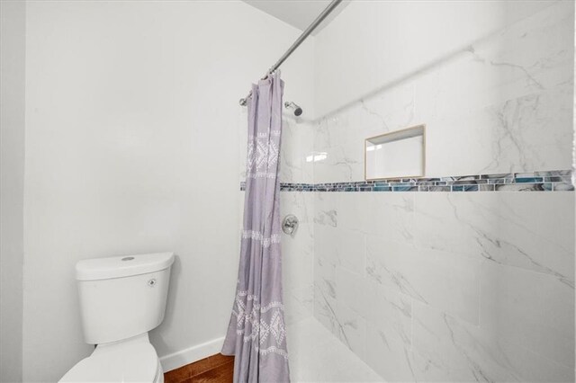 bathroom featuring toilet and curtained shower