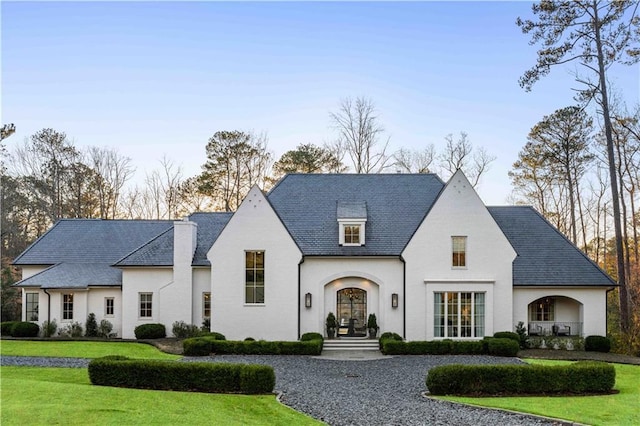 french country home with a high end roof and a front yard