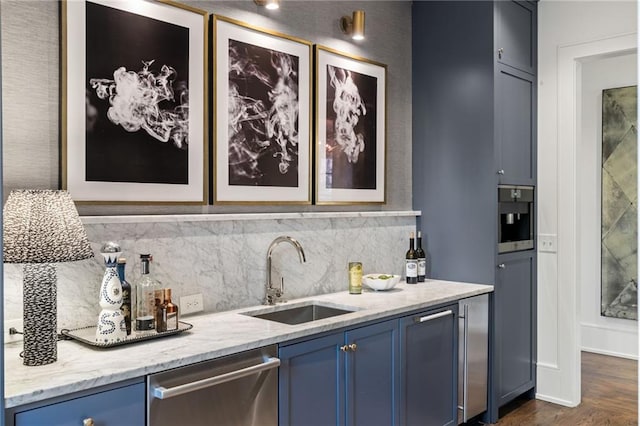 kitchen featuring light stone counters, blue cabinetry, dark wood-style flooring, a sink, and dishwasher