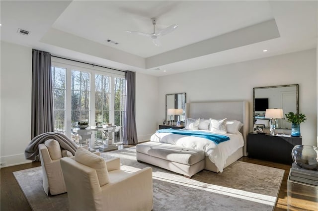 bedroom with recessed lighting, a tray ceiling, visible vents, and wood finished floors