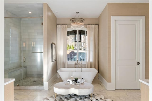 bathroom featuring baseboards, a freestanding tub, a stall shower, marble finish floor, and a chandelier