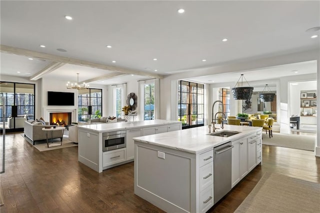 kitchen with built in microwave, open floor plan, a center island with sink, and a sink