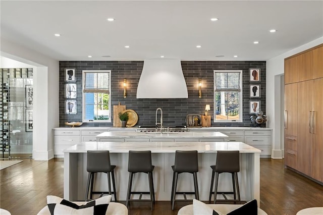 kitchen with decorative backsplash, a large island, dark wood-style floors, and premium range hood