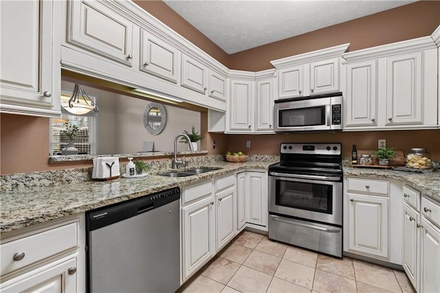 kitchen with a textured ceiling, light tile patterned floors, a sink, white cabinets, and appliances with stainless steel finishes