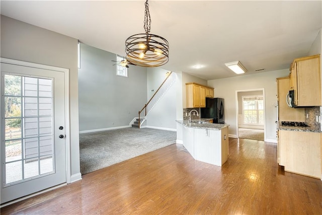 kitchen featuring black refrigerator, light brown cabinets, backsplash, and kitchen peninsula