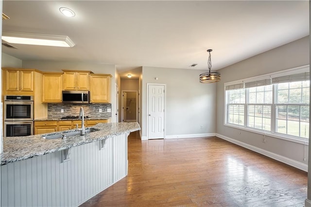 kitchen with light stone countertops, sink, tasteful backsplash, a breakfast bar, and appliances with stainless steel finishes