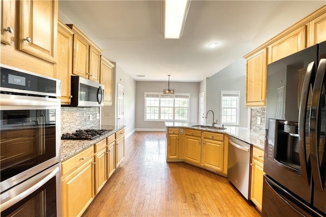 kitchen featuring sink, decorative backsplash, light stone countertops, decorative light fixtures, and stainless steel appliances