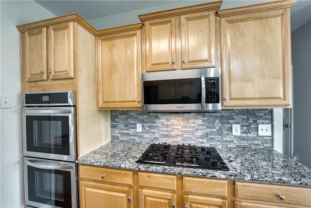 kitchen featuring stainless steel appliances, tasteful backsplash, and dark stone counters