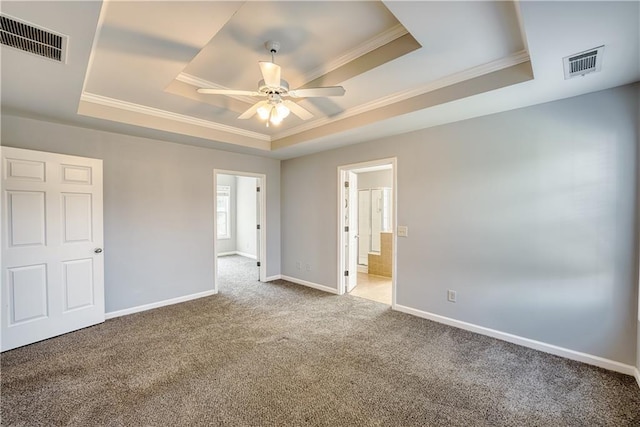 unfurnished bedroom featuring carpet, a raised ceiling, ensuite bath, ceiling fan, and ornamental molding